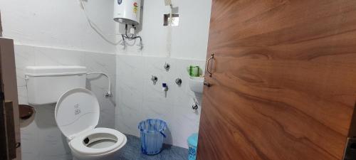 ein Badezimmer mit einem weißen WC und einer Holztür in der Unterkunft Rongo Orange Valley Camp&Cottages in Jhalong