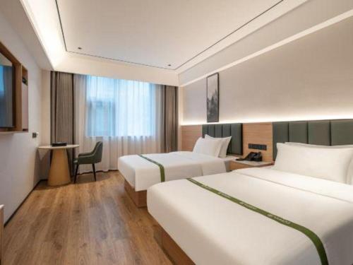ein Hotelzimmer mit zwei Betten und einem Schreibtisch in der Unterkunft GreenTree Inn Bengbu Huaihe Walking Street in Bengbu