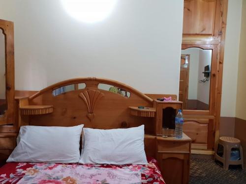 a bed with a wooden headboard in a room at Moon Rise Hotel in Dargai
