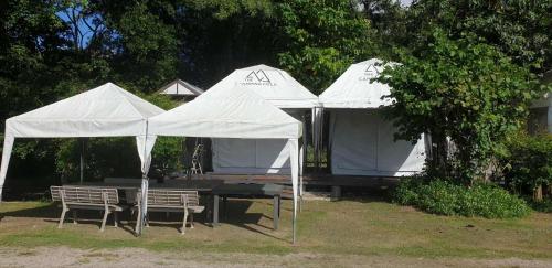 a group of white tents with a table and chairs at The Camping Field in Ban Kluai