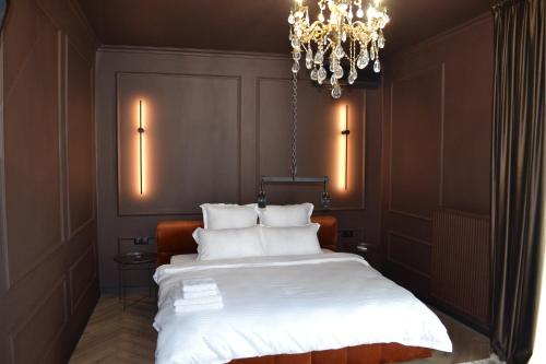 a bedroom with a bed with white sheets and a chandelier at Park Gate apartment in Chernivtsi