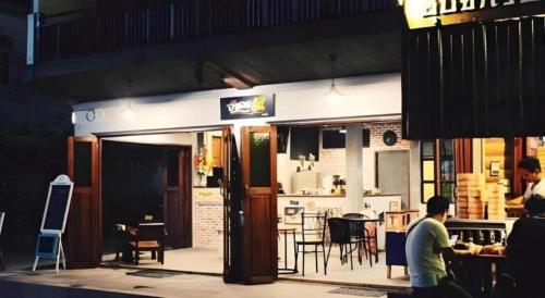 un hombre sentado frente a un restaurante con una mesa en Remember Loei Love, en Chiang Khan