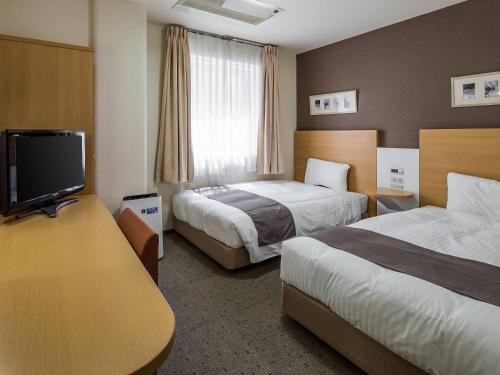 a hotel room with two beds and a flat screen tv at Comfort Hotel Tendo in Tendo