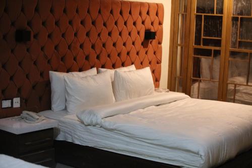 Un dormitorio con una cama grande con un cabecero grande. en Hotel Emerlad Crown, en Dargai