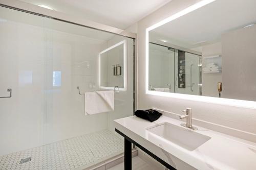 een witte badkamer met een wastafel en een douche bij The Lux Hotel & Conference Center, an Ascend Collection Hotel in Waterloo