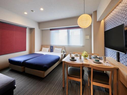 a hotel room with a bed and a table and a tv at Minn Nishi Kasai in Tokyo
