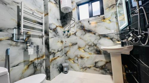 a marble bathroom with a toilet and a sink at Welcome to your home away from home! in Kabul