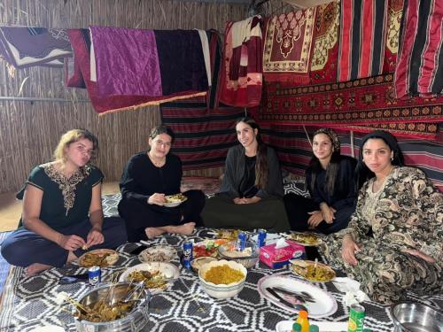 a group of people sitting around a table with food at Sama Al Sharqiyah Camp in Al Wāşil