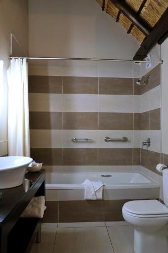 a bathroom with a tub and a toilet and a sink at Hazyview Sun in Hazyview