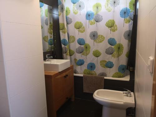 ein Badezimmer mit einem Waschbecken und einem Duschvorhang mit Sonnenschirmen in der Unterkunft La Casa del Mirlo Azul - Peñíscola in Peñíscola
