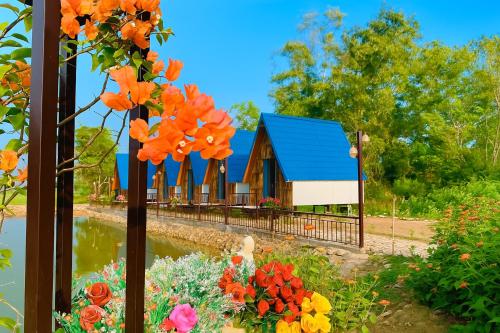 a building with a blue roof and flowers in front at Giáp Hoài Homestay Suối Khoáng Nóng Bản Hốc in Yên Bái
