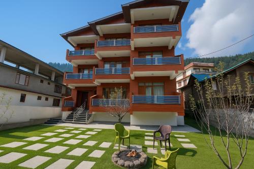 a building with a yard with two chairs in front of it at The Manali Suits & Villa - Luxury Stay Away From City Hustle in Manāli
