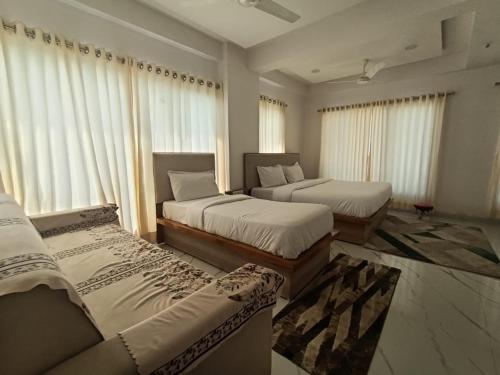 duas camas em um quarto com janelas e cortinas. em Hotel Sanwariya em Gandhinagar