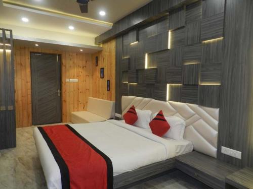 a bedroom with a large white bed with red pillows at Hotel The Novelty in Kānpur