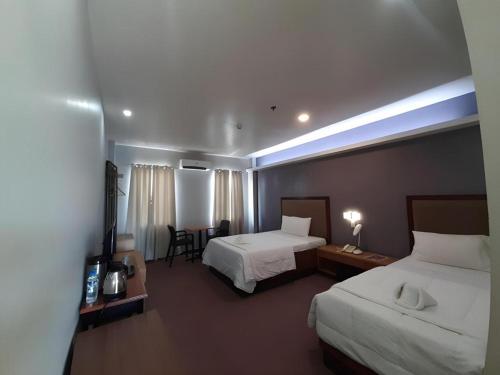 een hotelkamer met twee bedden en een tafel bij Hotel Camila 2 in Dipolog