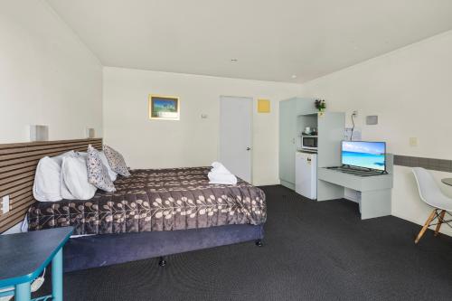 a hotel room with a bed and a desk with a computer at Birchwood Spa Motel in Rotorua