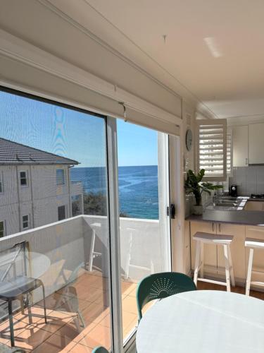 a kitchen and dining room with a view of the ocean at Beachside Apartment Blackwoods Beach in Cronulla