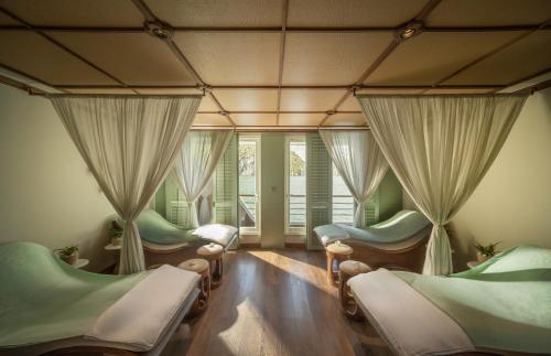 a room with four beds and windows with curtains at Bhaya Soul - Wellness Inclusive Cruise in Ha Long