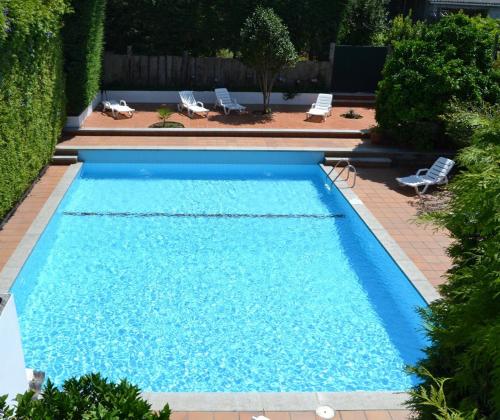 a large blue swimming pool with two lawn chairs at Hotel Amandi in O Grove