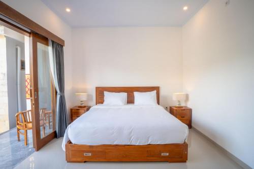 a bedroom with a large bed with white sheets at Moringa Pandawa Guest House in Ungasan
