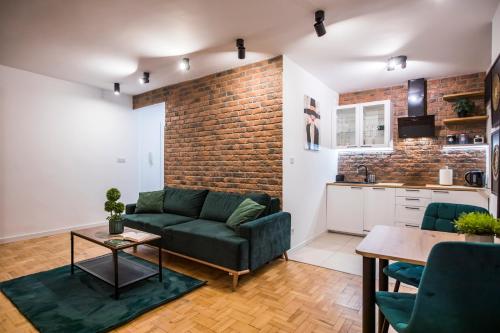 een woonkamer met een groene bank en een bakstenen muur bij Clara in Rzeszów