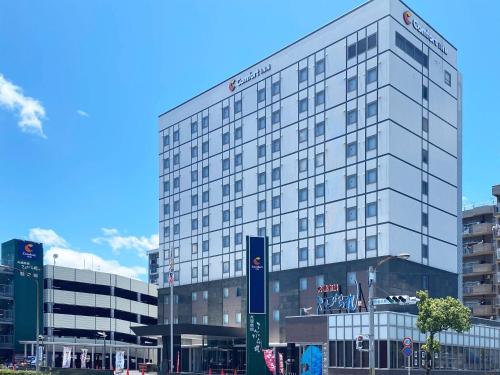 a tall white building with a sign in front of it at Comfort Inn Kagoshima Taniyama in Kagoshima