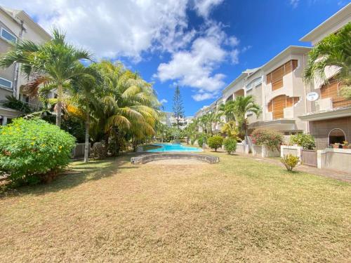 a backyard with a swimming pool and palm trees at Grand Bay 4Bed Triplex Villa with Community Pool in Grand Baie