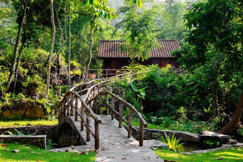 Un puente de madera sobre un camino frente a una casa. en HGNI Valley - Thung Lũng Tự Do, en Làng Xa