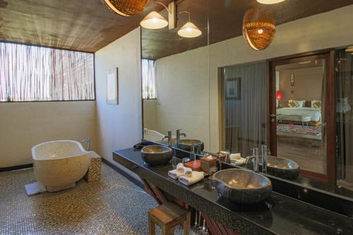 Un baño con tres lavabos y un espejo grande. en Sky Suites, en Seminyak