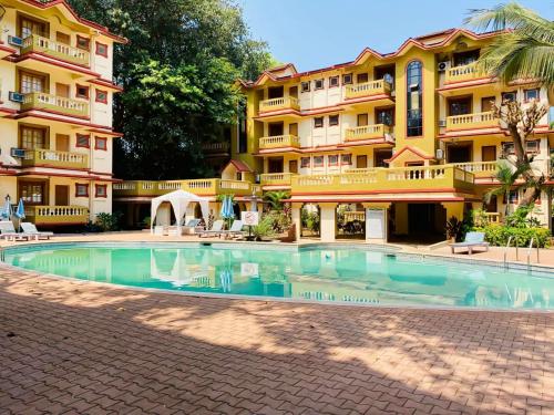 a swimming pool in front of a building at Candolim apartment in Candolim
