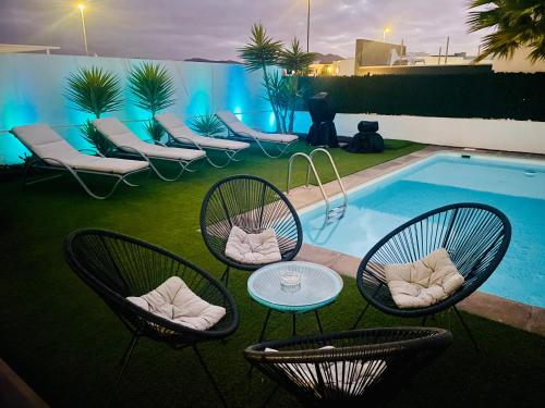 a group of chairs and tables next to a pool at Villa Neo - Private Pool - 8 minutes Corralejo, mini Gym!! in Villaverde