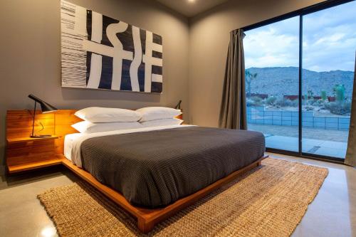 a bedroom with a large bed and a large window at The Coza by Fieldtrip - Modern Retreat w Pool Spa in Joshua Tree