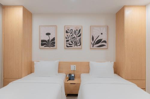 two beds in a room with three pictures on the wall at Bcons City Hotel in Dĩ An