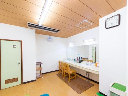 een kamer met een tafel en stoelen en een klok bij Tabist Marutora Bekkan Nishio Kira in Yoshida