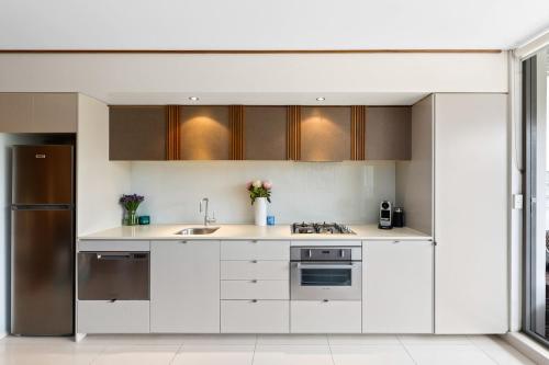 a kitchen with white cabinets and stainless steel appliances at Drews Bondi Beach Pad Music Inspired in Sydney
