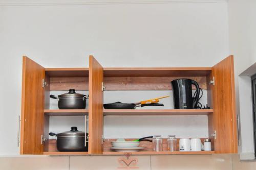 a kitchen shelf with pots and pans on it at Monalisa Studio Apartments in Gatunga