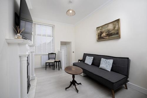 a living room with a black couch and a table at Beautiful 1-bed Apartment in Lincoln by Renzo, Lincoln Cathedral, Free Parking! in Lincoln