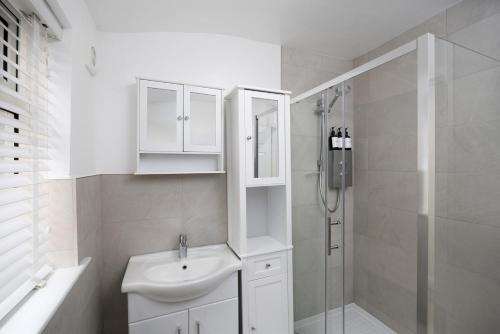 a white bathroom with a sink and a shower at Beautiful 1-bed Apartment in Lincoln by Renzo, Lincoln Cathedral, Free Parking! in Lincoln
