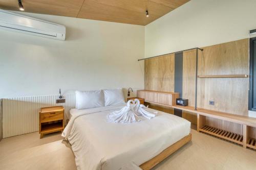 une chambre avec un grand lit blanc avec une tête de lit en bois dans l'établissement Bingo Bingin Cozy 1BR Townhouse Nearby Bingin Beach, à Bingin Beach