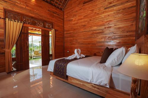 ein Schlafzimmer mit einem Bett und einer Holzwand in der Unterkunft Puri Bucuana Villa in Bedahulu