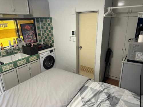 a small kitchen with a bed and a washing machine at 御嶽ハウス in Tokyo