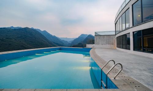 a swimming pool in front of a building with mountains at Zhangjiajie Valley Secret Resort in Zhangjiajie
