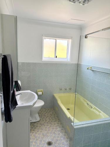 a bathroom with a tub and a sink at 2 Bedroom Apartment - Heart of Cronulla in Cronulla