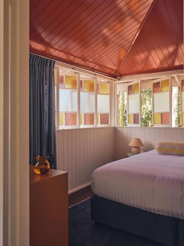 a bedroom with a bed and some windows at Halse Lodge Noosa Heads in Noosa Heads