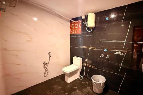 a bathroom with a toilet and a phone on the wall at Metro Club Resort in Kāmānayakkanpālaiyam