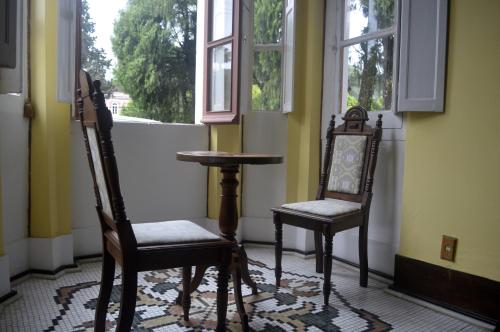 two chairs and a table in a room with a window at Pousada Imperial Koeler in Petrópolis