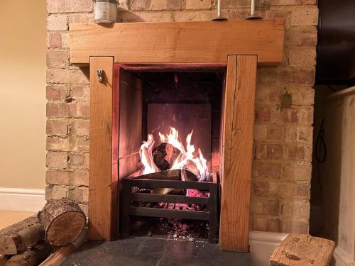 a brick fireplace with a fire in it at Oak Crest, 2 bedrooms, log fire, scenic views near Chapel Down in Rolvenden