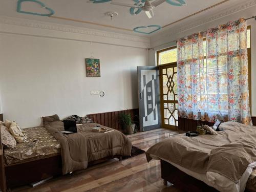 Un dormitorio con dos camas y una ventana en La Casa by Cosmic Kriya, en Bīr