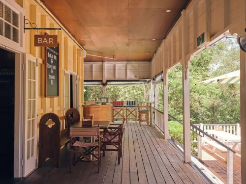 a deck with tables and chairs on a building at Halse Lodge Noosa Heads in Noosa Heads
