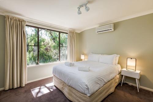 a bedroom with a bed and a large window at Tranquil Waters in Quindalup